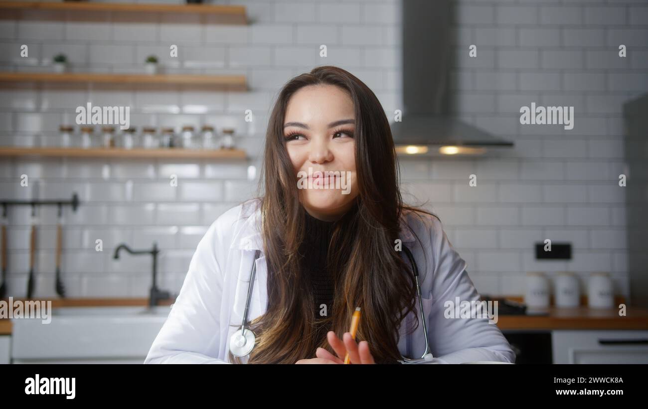 Weibliche asiatische Ärztin tragen weiße Uniform mit Stethoskop, die Videokonferenz führt, online mit dem Patienten chatten, die Kamera in die Webcam schaut. Fernbedienungsgerät Stockfoto