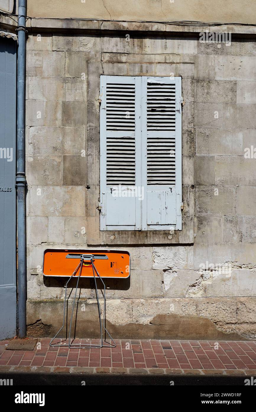 Geschlossene graue Fensterläden und kleiner oranger Klapptisch Stockfoto