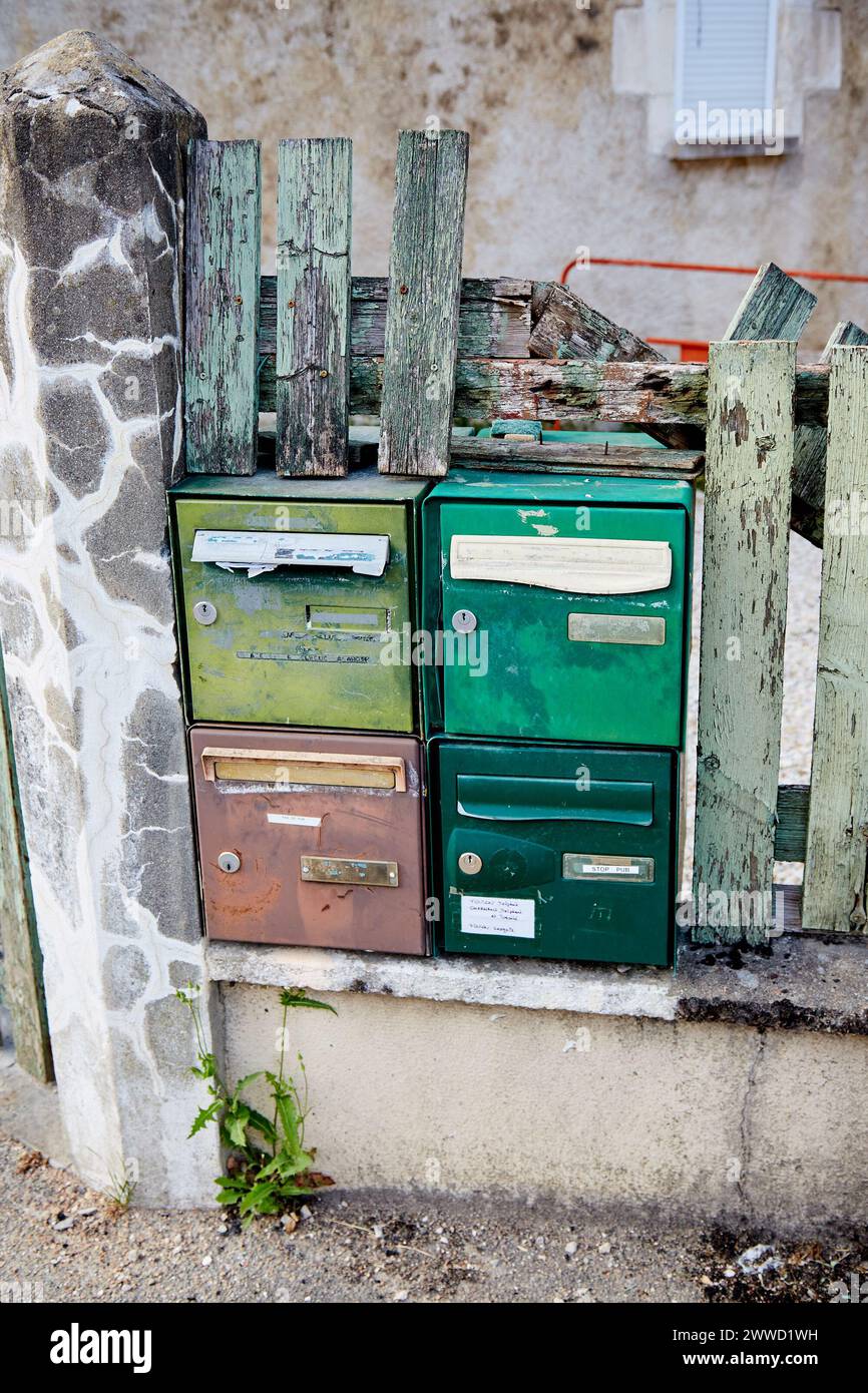 Grüne und braune Briefkästen in einem kaputten alten Zaun Stockfoto