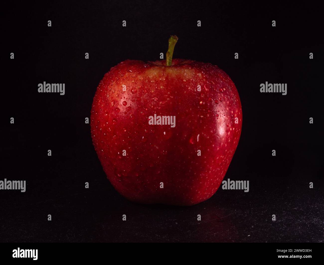 Ein köstlicher frischer und knuspriger roter Apfel mit Wassertropfen. Schwarzer Hintergrund. Stockfoto