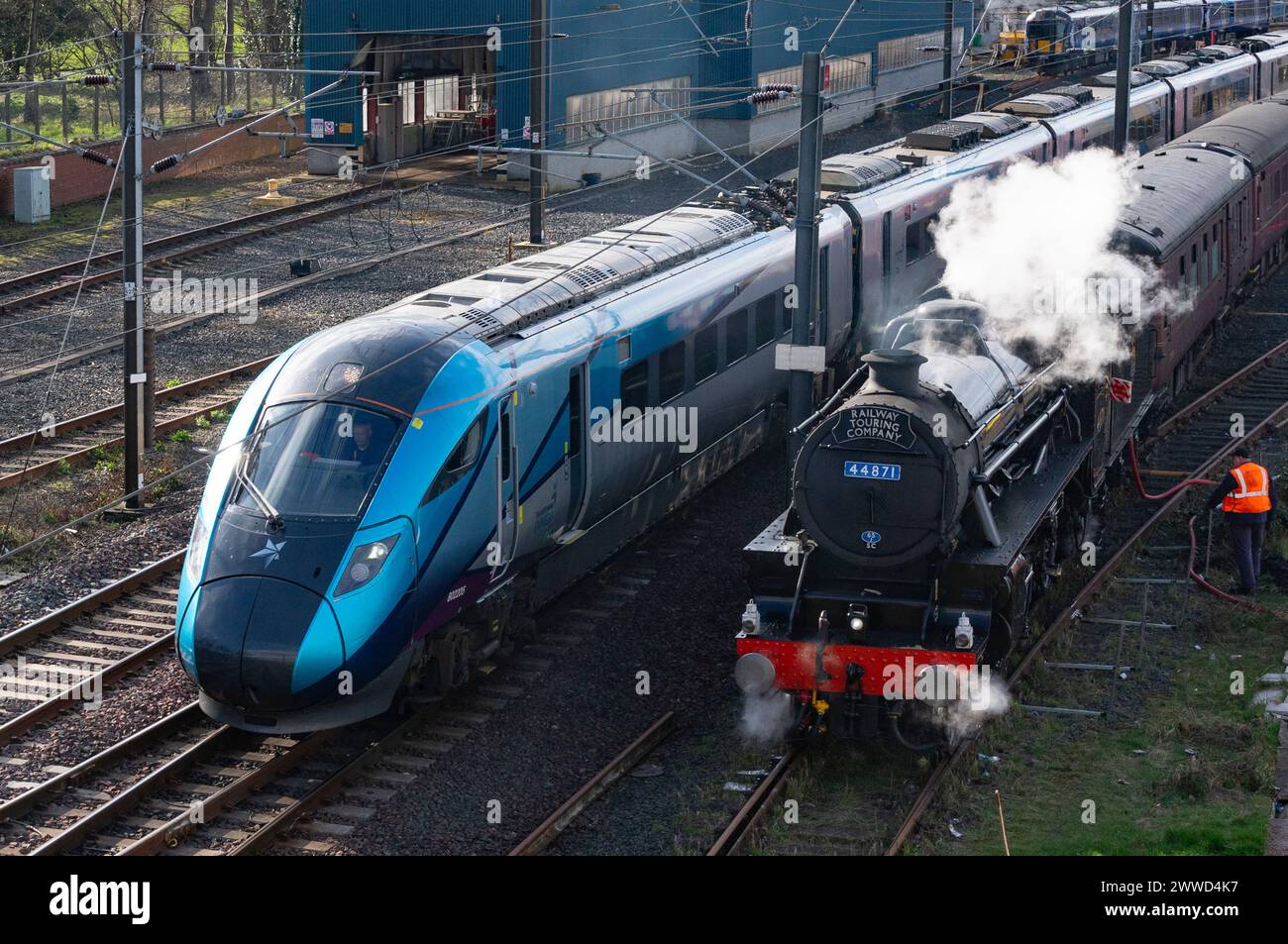 Edinburgh, Schottland, Großbritannien. März 2024. Eine seltene Black 5 (oder Class 5 Mixed Traffic) Dampflokomotive Nummer 44871, die von der Railway Touring Company betrieben wird, zieht Waggons mit Dampfzugliebhabern auf einem Tagesausflug von York nach Edinburgh. Kontrast zwischen alten und neuen Zügen, da ein TransPennine Express-Zug die Lokomotive überquert, wenn sie bewässert wird und Kohle auf dem Joppa-Anschlussgleis in Edinburgh annimmt. Iain Masterton/Alamy Live News Stockfoto