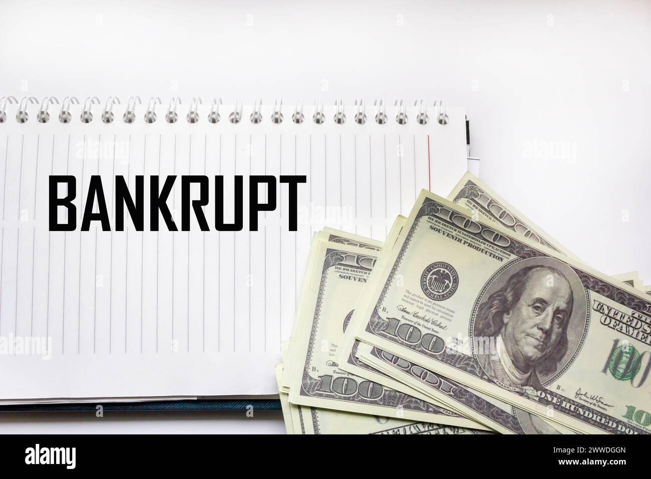BANKROTT - das Wort auf dem Hintergrund von Gelddollar, Notizblock. Geschäftskonzept Stockfoto