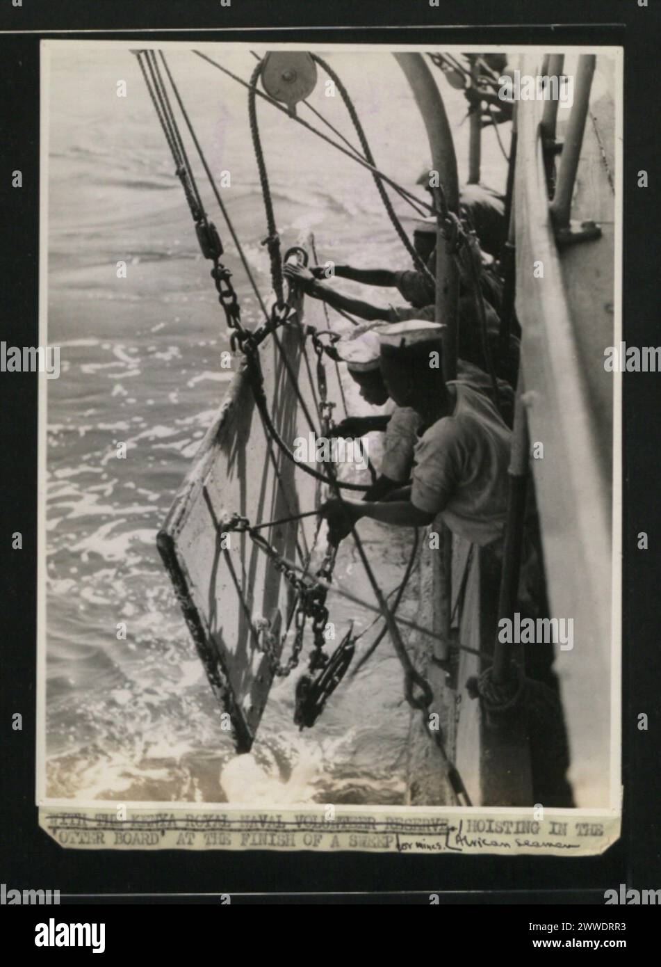 Im Jahr 1945 hebt ein afrikanischer Seemann das Otter Board nach einer Minenräumung und demonstriert die Abholarbeiten der Marine und die Sicherheitsverfahren für den Seeverkehr. Stockfoto