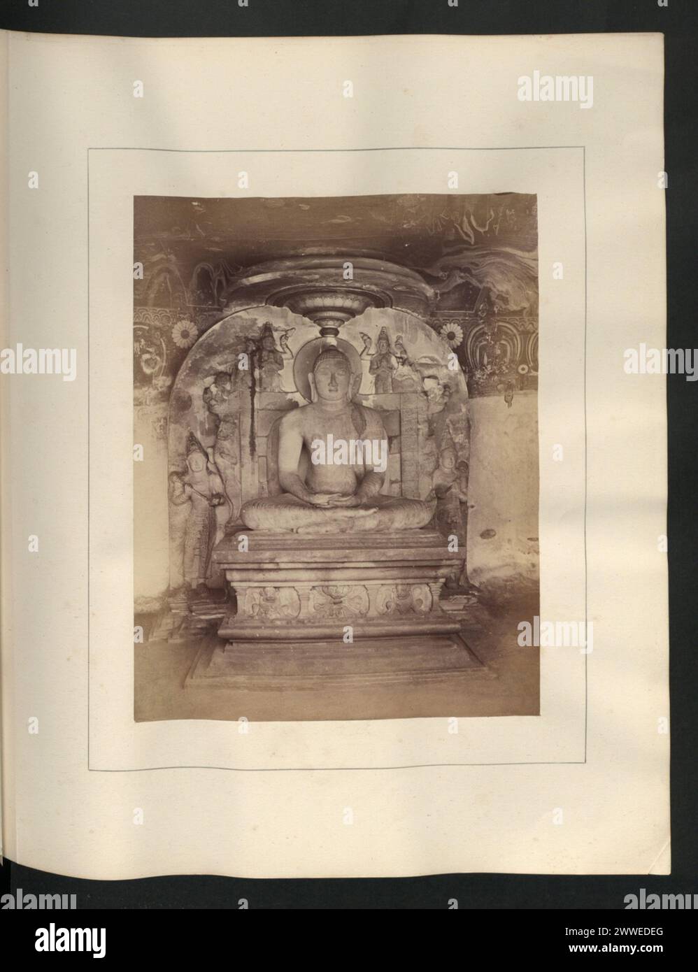 Eine aus Felsen geschnittene Buddha-Figur, 1,5m hoch, sitzt auf einem 1,5m langen und 1,5m hohen Sockel in der Cella des Gal-wiharé-Tempels mit den dazugehörigen Gottheiten und Löwen. Stockfoto