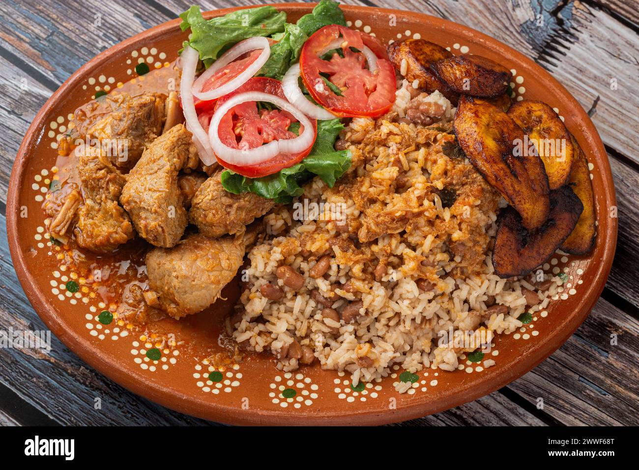 Reiscongri mit Schweinefleisch Frikassee, Salat und frittierter reifer Kochbanane. Typisch kubanisches Essen. Stockfoto