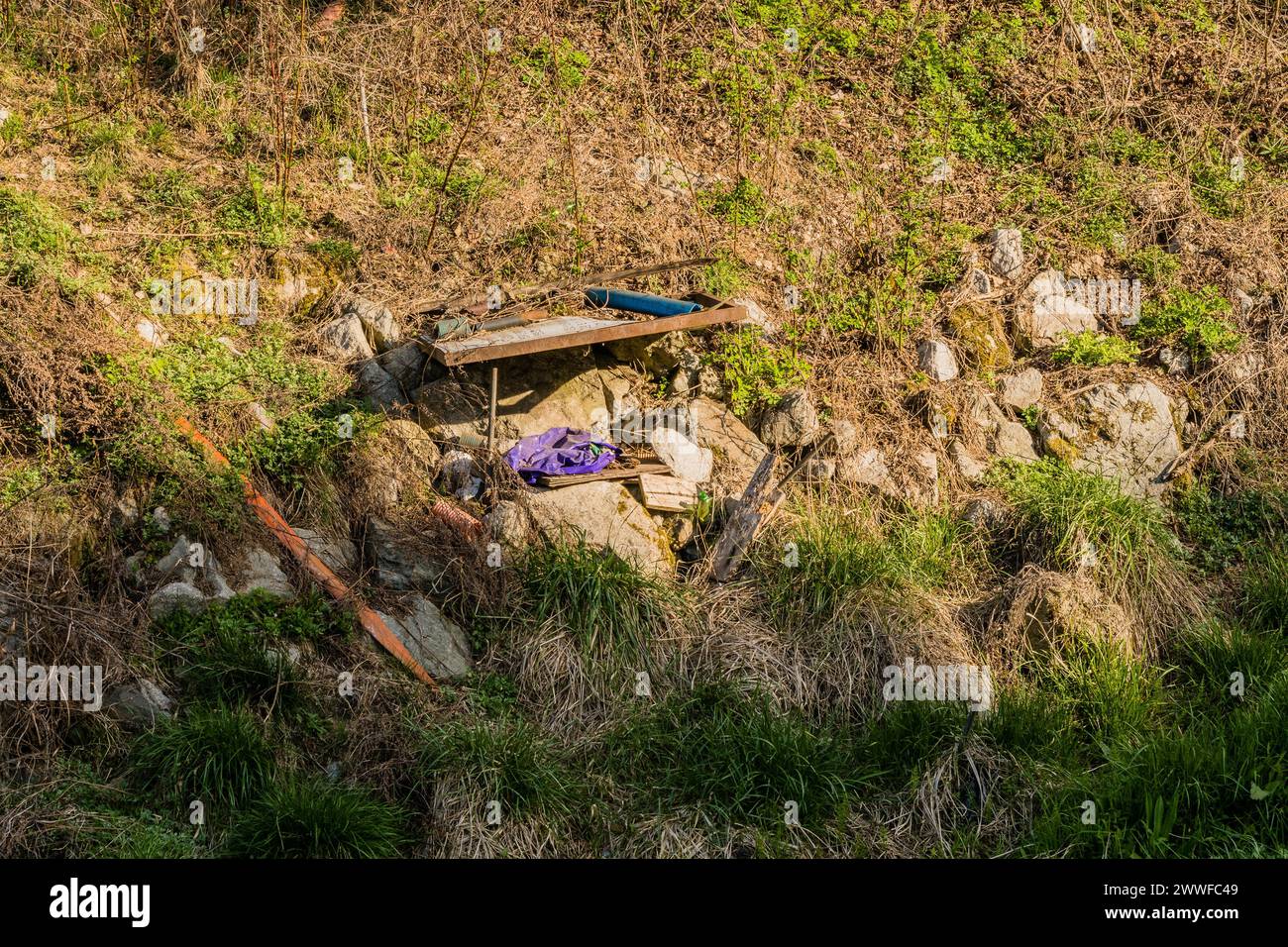 Weggeworfene Gegenstände und Müll sind in Südkorea über einen Außenbereich mit Gras und Felsen verteilt Stockfoto