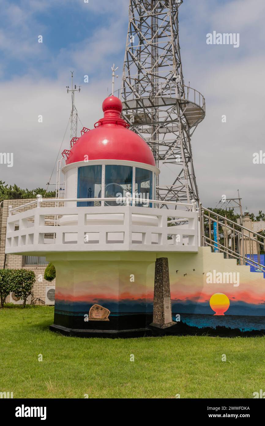 Ein roter Leuchtturmnachbau vor einem Kommunikationsturm unter klarem Himmel in Ulsan, Südkorea Stockfoto