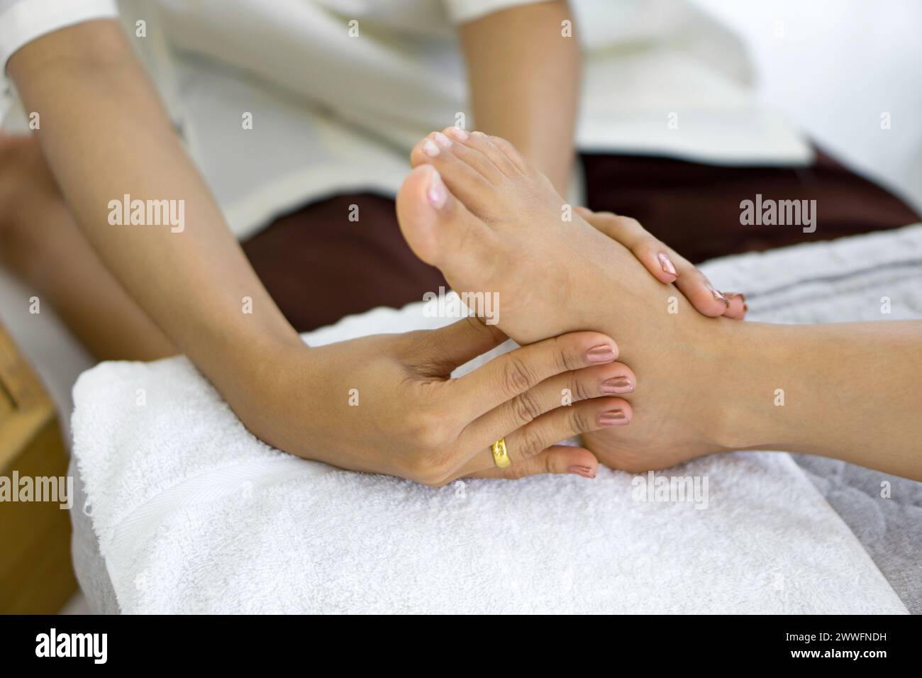 Eine Person gibt einer anderen Person eine Fußmassage auf einem Handtuch. Körperpflegebehandlung durch thai-Massage. Stockfoto