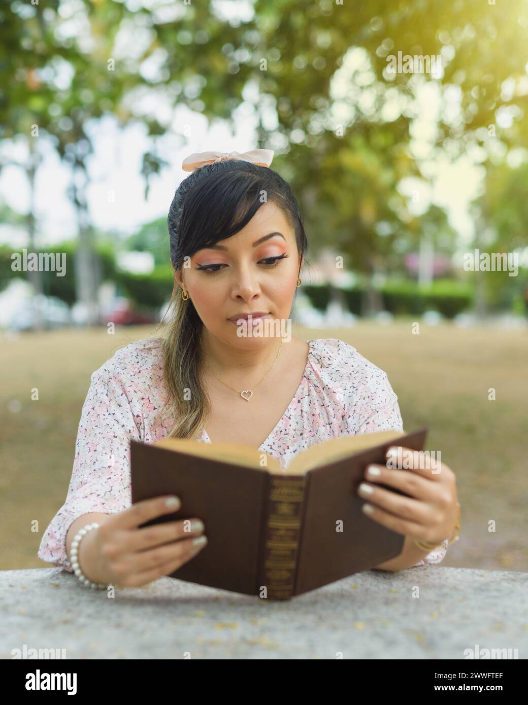 Frau, die am Parktisch sitzt und ein Buch liest. Weltbuchtag. Lesekonzept. Stockfoto