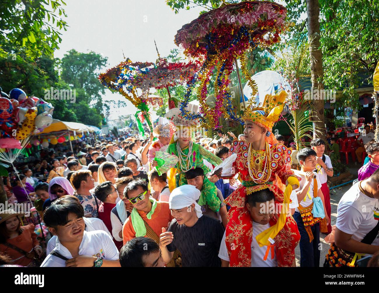 Chiang Mai, Thailand. März 2024. Junge ethnische Shan-Jungen in bunten Kostümen werden auf den Schultern ihrer Familienmitglieder getragen, während einer jährlichen langen Prozession des POY sang, ein traditioneller Übergangsritus für Jungen, die als buddhistische Novizen im Wat Ku Tao Tempel initiiert werden. POY Sang Long ist eine buddhistische Novizen-Ordinationszeremonie der thailändischen Yai-Stämme, aber anders als jede andere Zeremonie dieser Art im Land. Junge zwischen 7 und 14 Jahren werden als Novizen geweiht, um buddhistische Lehren zu lernen. Quelle: SOPA Images Limited/Alamy Live News Stockfoto