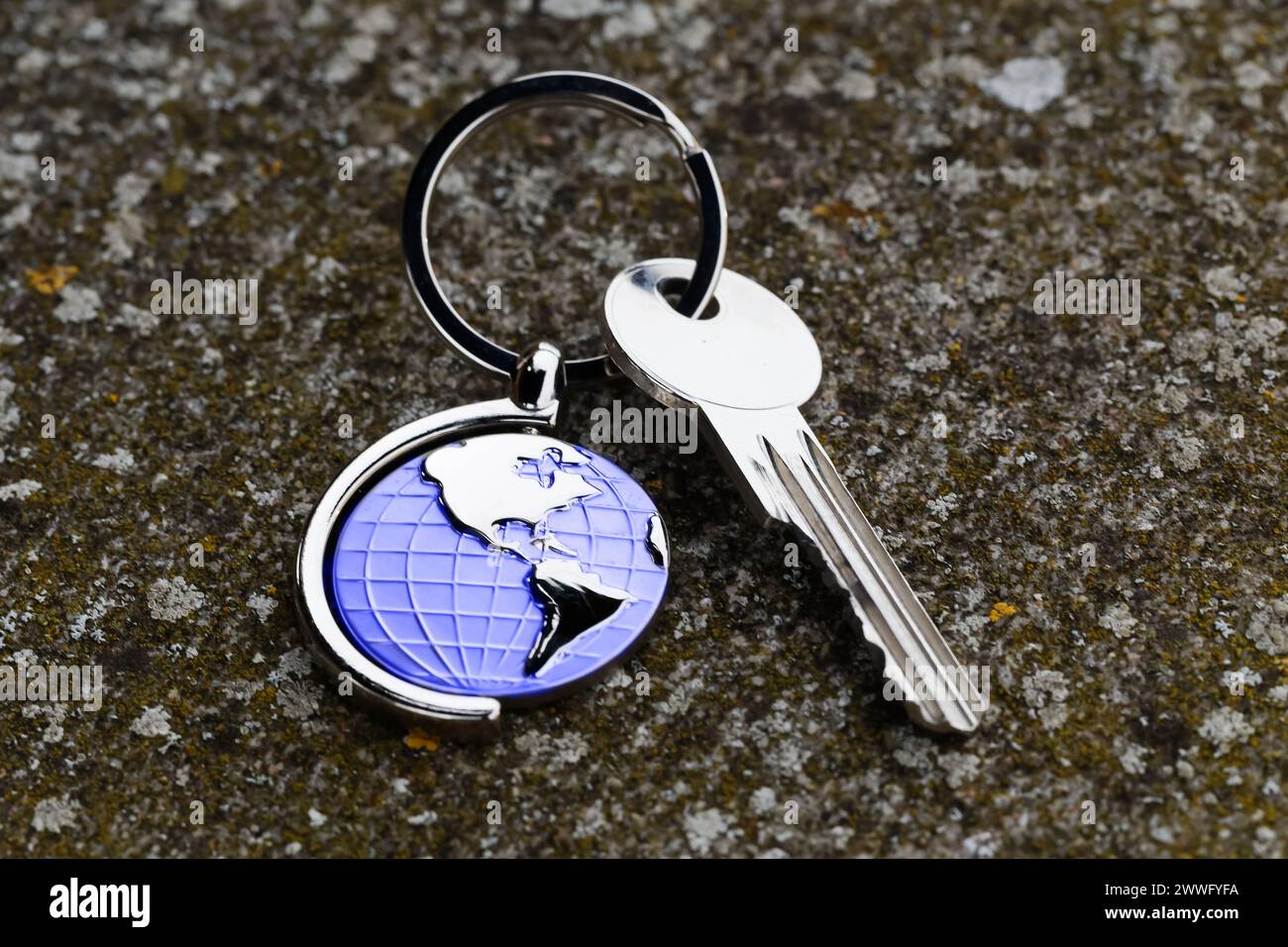 Weltsymbol mit silbernen Schlüsseln auf abstraktem Hintergrund. Immobilienkonzept Stockfoto