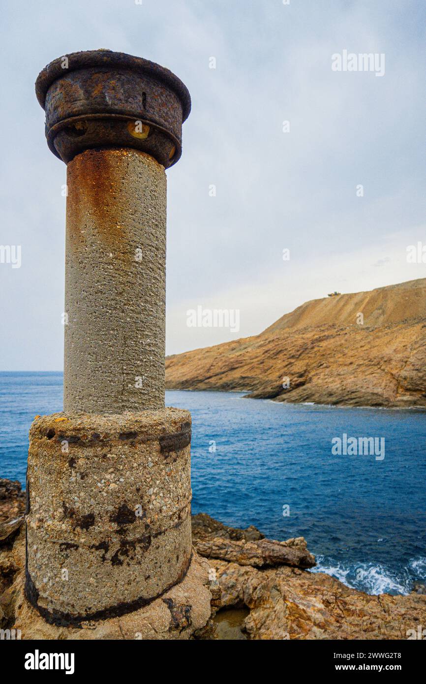 Eine korrodierte zylindrische Struktur steht allein, ein Wächter am Meer. Stockfoto