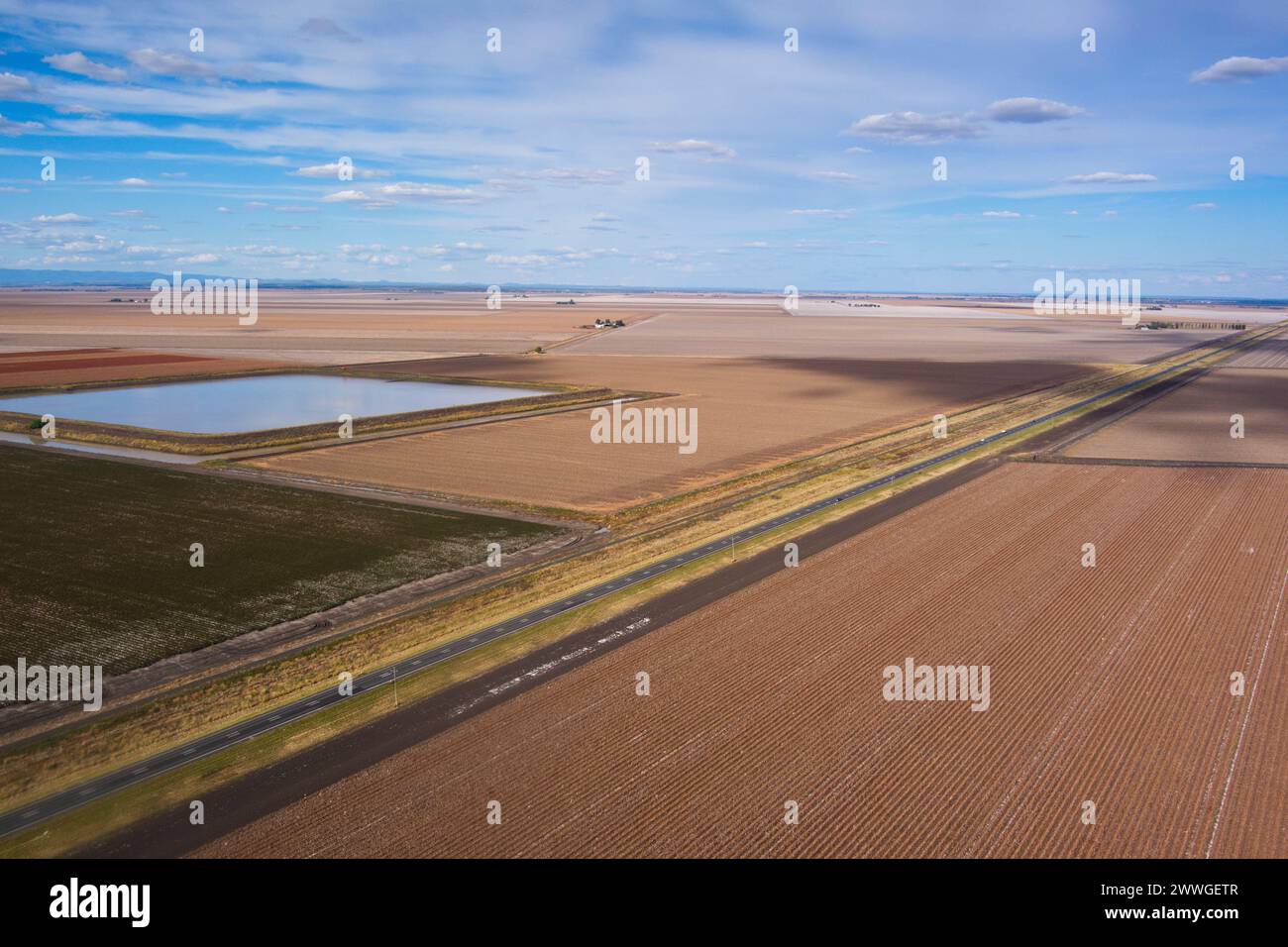 Luftlinie des Warrego Highway, der durch geerntete Baumwollfelder mit Wasserspeicher in der Nähe von Dalby Queensland Australia führt Stockfoto