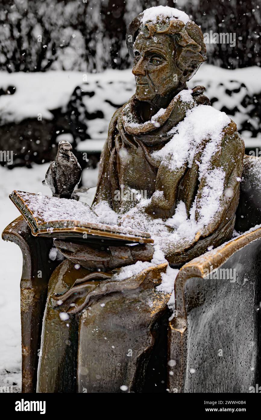 Eine Bronzestatue eines Gelehrten in der Nachsicht, bedeckt mit Schneeflocken vor einer verschwommenen Winterkulisse. Stockfoto Eine Bronzestatue eines Gelehrten in der Nachsicht, bedeckt mit Schneeflocken vor einer verschwommenen Winterkulisse. Stockfoto