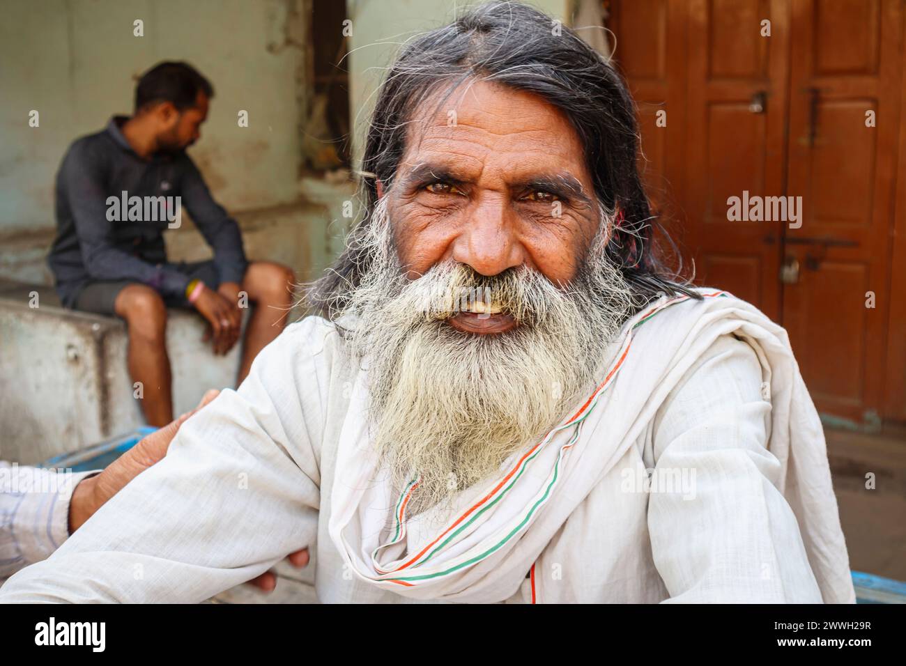 Schwer bärtige ältere Indianer in typischer Alltagskleidung sitzen am Straßenrand in einer Stadt im Stadtteil Umaria in Madhya Pradesh, Indien Stockfoto