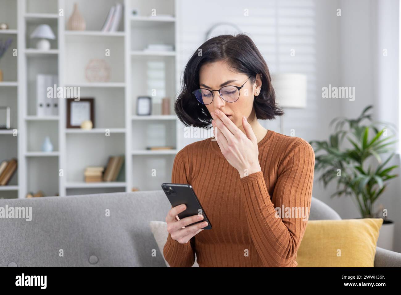 Eine sichtbar beunruhigte Frau, die ein Telefon hält und Verwirrung und Besorgnis schildert, möglicherweise nachdem sie beunruhigende Nachrichten erhalten hatte. Stockfoto