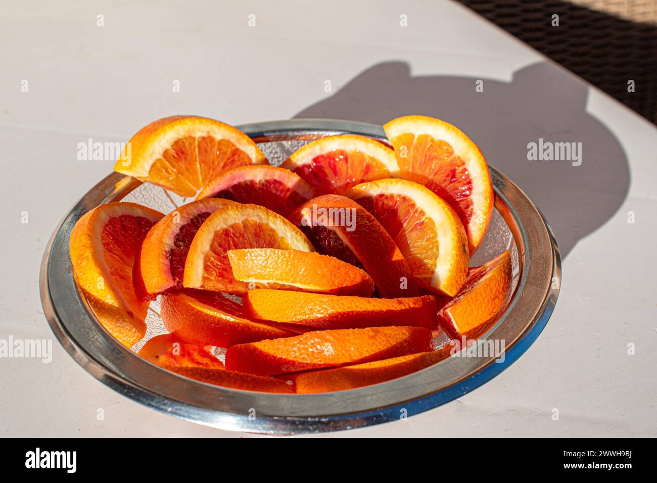 Eine Glasschale voller frischer Orangenscheiben im Sonnenlicht Stockfoto