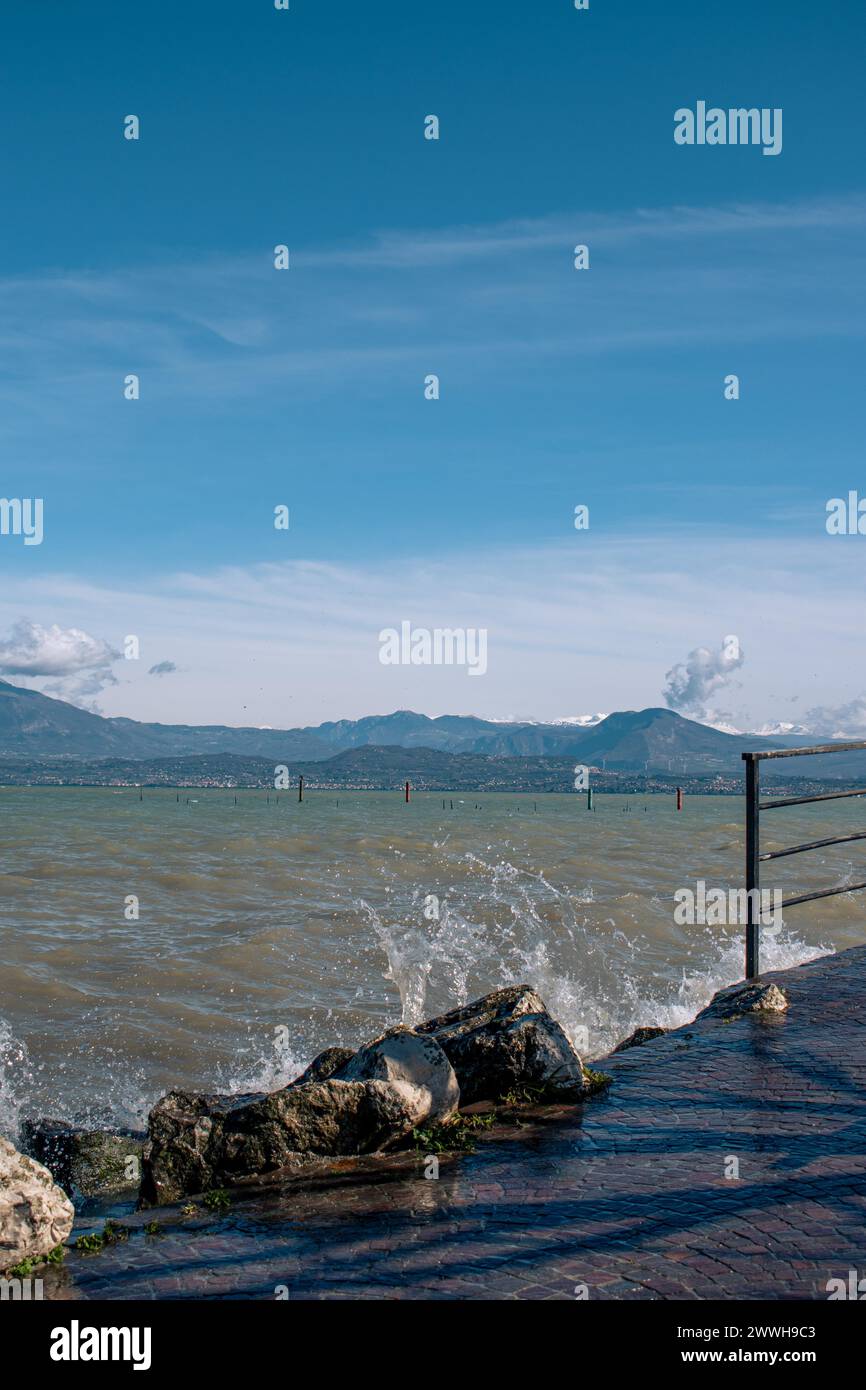 Rauschende Wellen treffen auf Felsen am Ufer des Gardasees, Sirmione, Gardasee, Italien Stockfoto