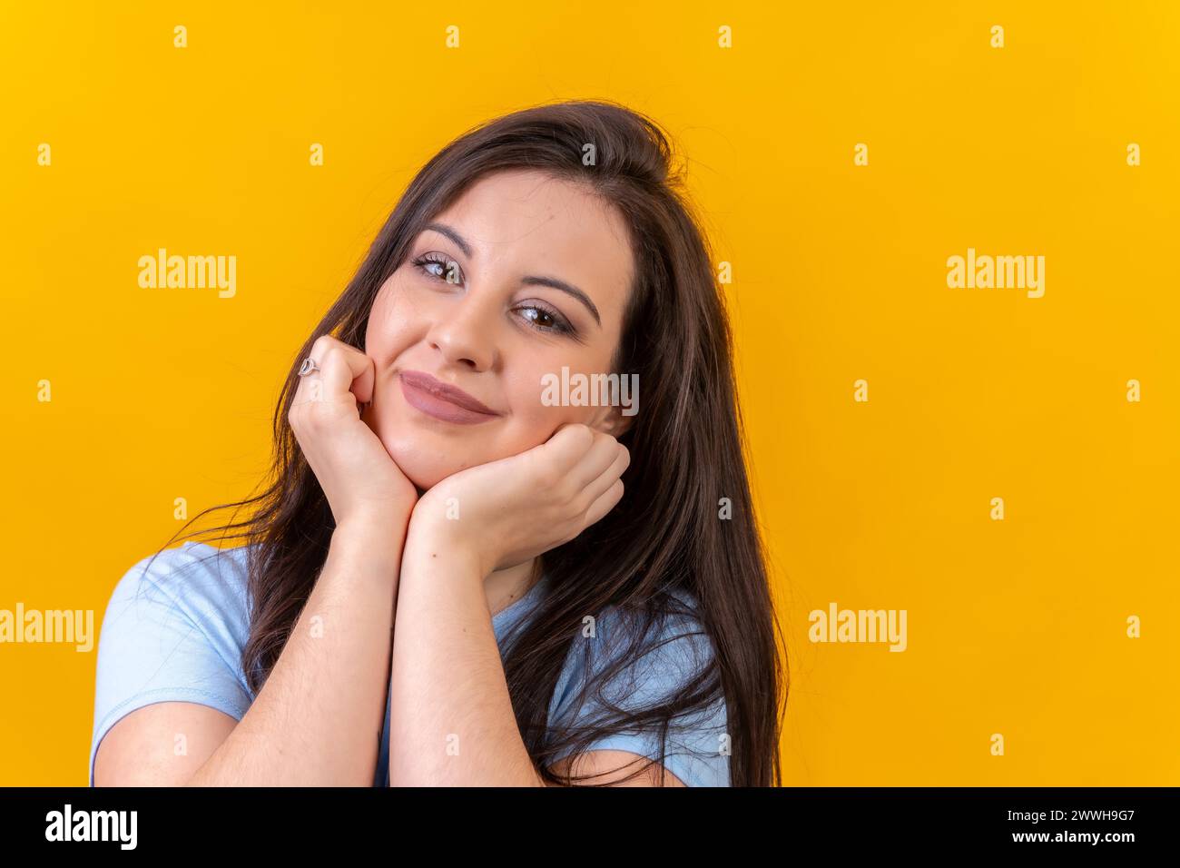 Studio-Porträt mit gelbem Hintergrund einer niedlichen Frau, die in die Kamera blickt Stockfoto