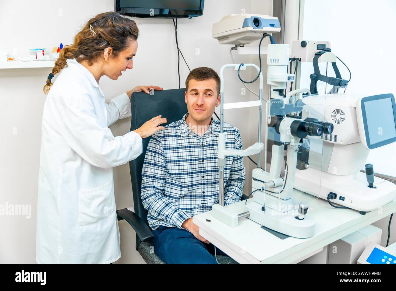 Erwachsener Mann sitzt und spricht mit einem Spezialisten bei einem Besuch beim Augenarzt Stockfoto