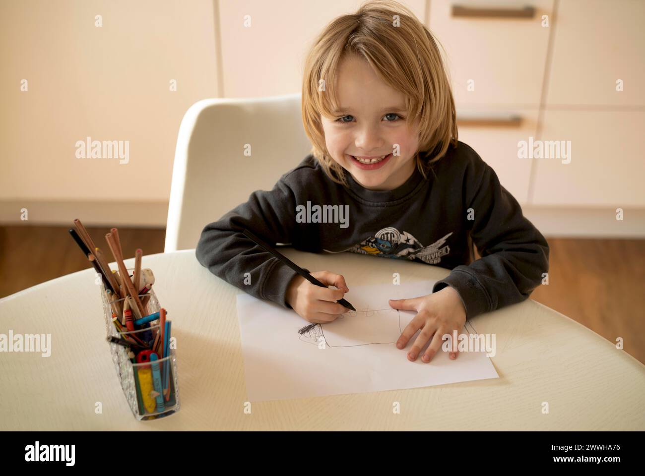 Innenfoto, Junge, 4-5 Jahre, blond, Malen auf Blatt Papier, Bleistifte, Tisch, lachend, fröhlich, Stuttgart, Baden-Württemberg, Deutschland Stockfoto