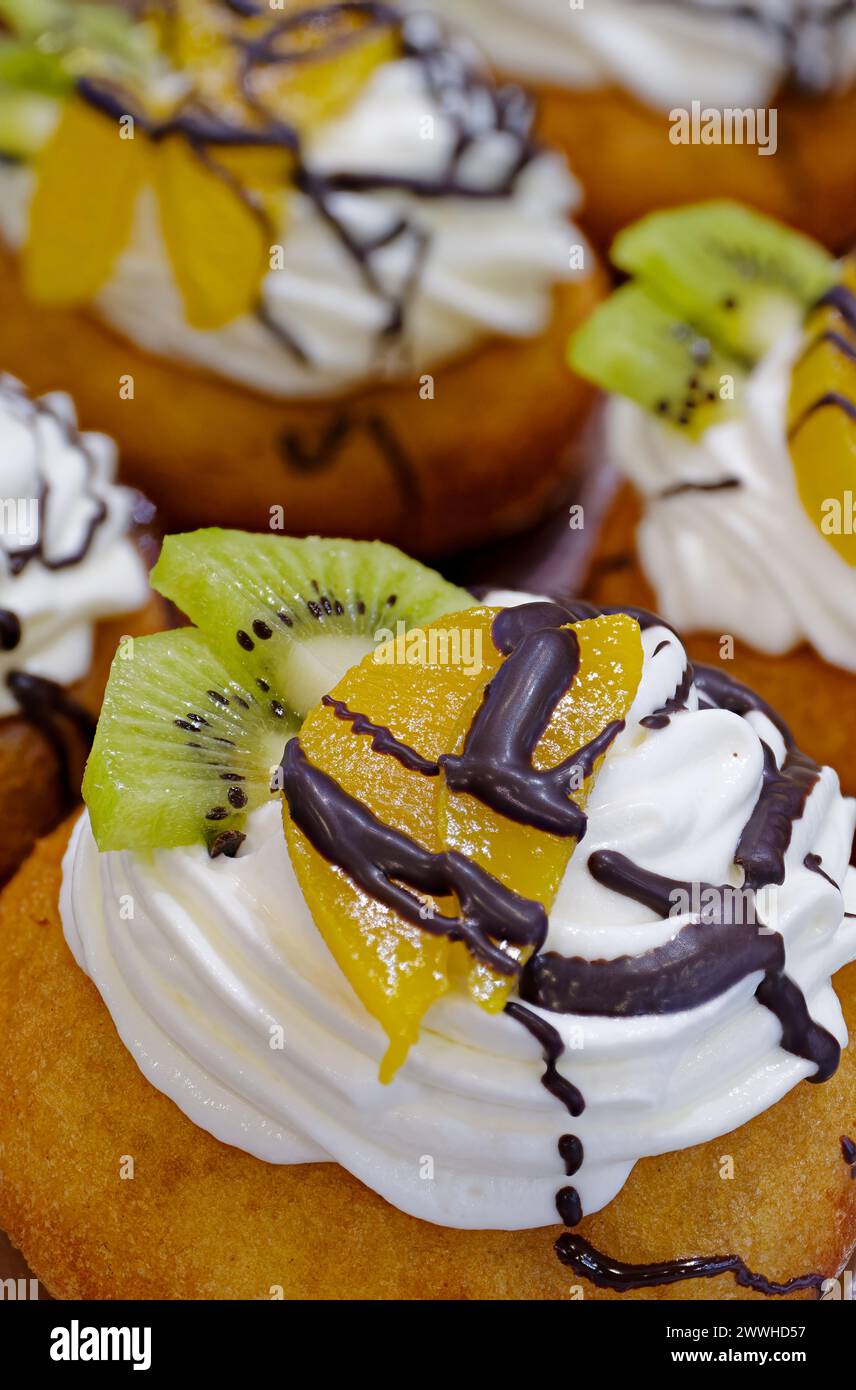Gruppe von Kuchen dekoriert mit Buttercreme, frischem Obst und Schokolade Stockfoto