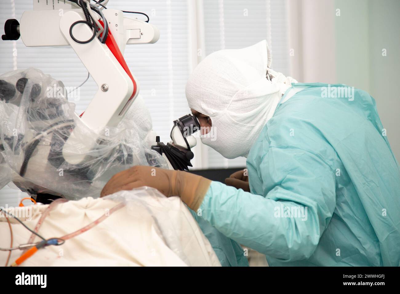 Ein Neurochirurg schaut während einer Operation in ein Mikroskop. Neurochirurgie und Mikrochirurgie. Echter Operationssaal. Stockfoto