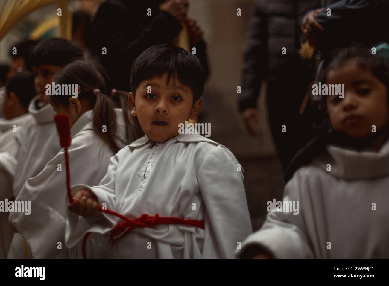 Barcelona, Spanien. März 2024. Junge Pönitenten aus der 'Gran Poder und Macarena Esperanza'-Bruderschaft gehen während der Palmensonntagsprozession in Barcelona mit Palmenzweig durch die Straße. Credit: Matthias Oesterle/Alamy Live News Stockfoto