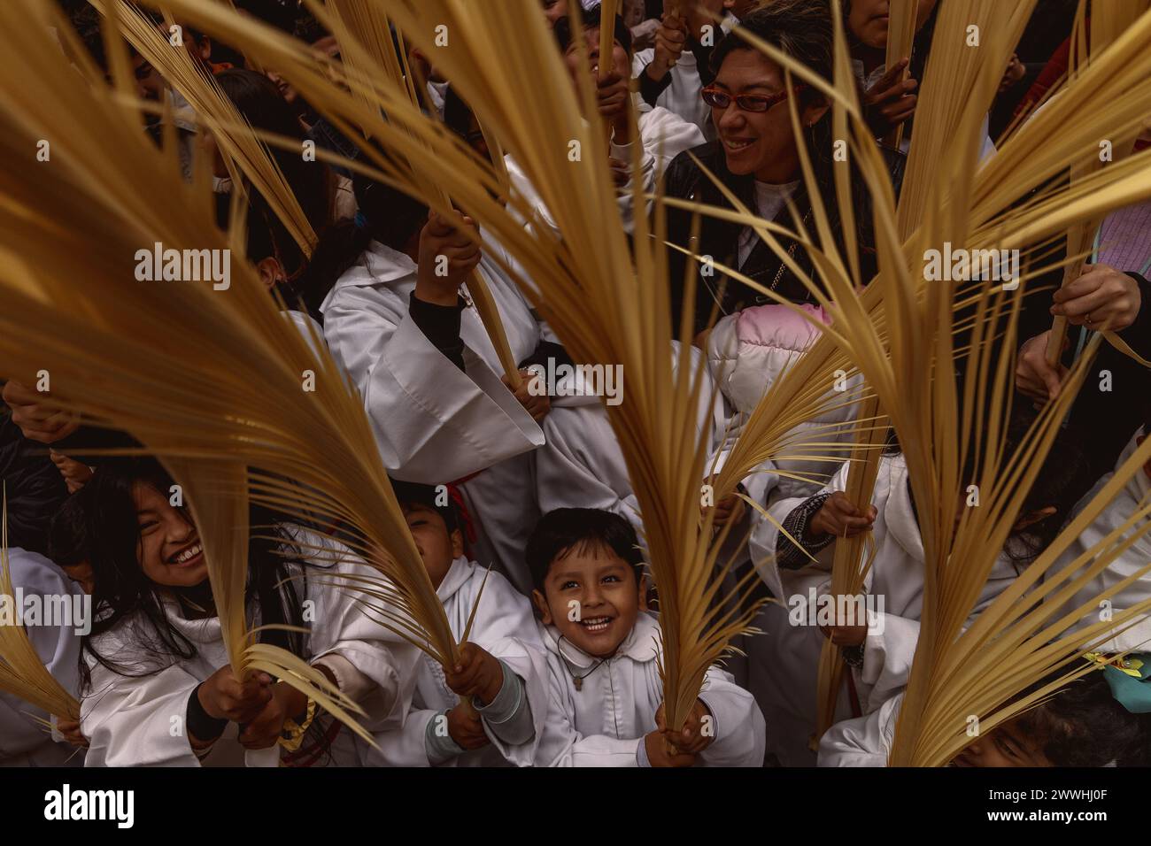 Barcelona, Spanien. März 2024. Junge Pönitenten der Bruderschaft Gran Poder und Macarena Esperanza winken Palmblätter, während der Priester sie am Ende der Palmensonntagsprozession in Barcelona segnet. Credit: Matthias Oesterle/Alamy Live News Stockfoto