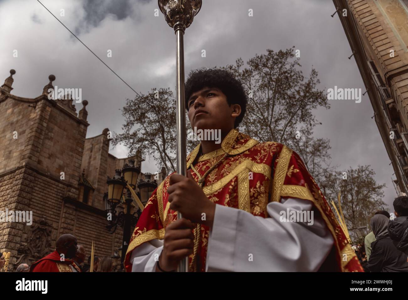 Barcelona, Spanien. März 2024. Ein junger Buße aus der Bruderschaft Gran Poder und Macarena Esperanza läuft während der Palmensonntagsprozession in Barcelona mit einem Palmenzweig durch die Straße. Credit: Matthias Oesterle/Alamy Live News Stockfoto