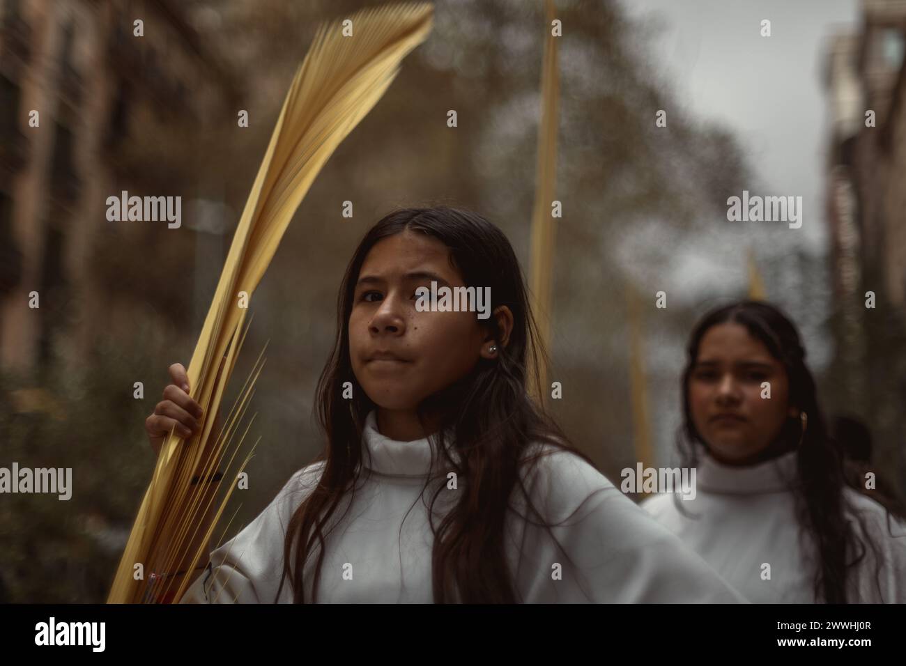 Barcelona, Spanien. März 2024. Junge Pönitenten aus der 'Gran Poder und Macarena Esperanza'-Bruderschaft gehen während der Palmensonntagsprozession in Barcelona mit Palmenzweig durch die Straße. Credit: Matthias Oesterle/Alamy Live News Stockfoto
