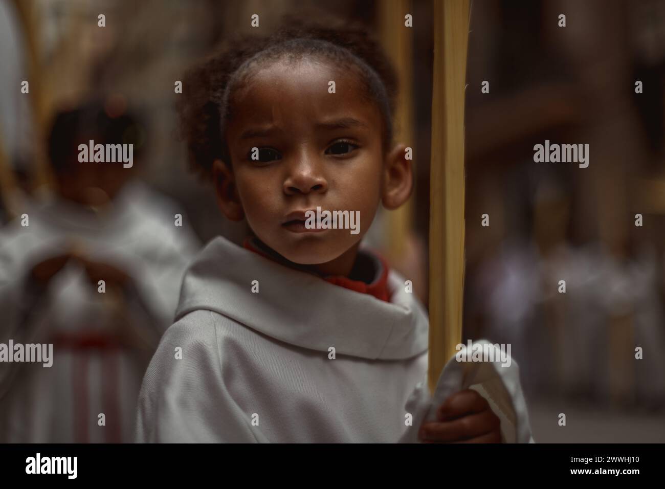 Barcelona, Spanien. März 2024. Ein junger Buße aus der Bruderschaft Gran Poder und Macarena Esperanza läuft während der Palmensonntagsprozession in Barcelona mit einem Palmenzweig durch die Straße. Credit: Matthias Oesterle/Alamy Live News Stockfoto