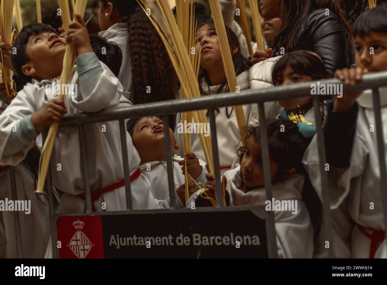 Barcelona, Spanien. März 2024. Junge Pönitenten der Bruderschaft Gran Poder und Macarena Esperanza winken Palmblätter, während der Priester sie am Ende der Palmensonntagsprozession in Barcelona segnet. Credit: Matthias Oesterle/Alamy Live News Stockfoto