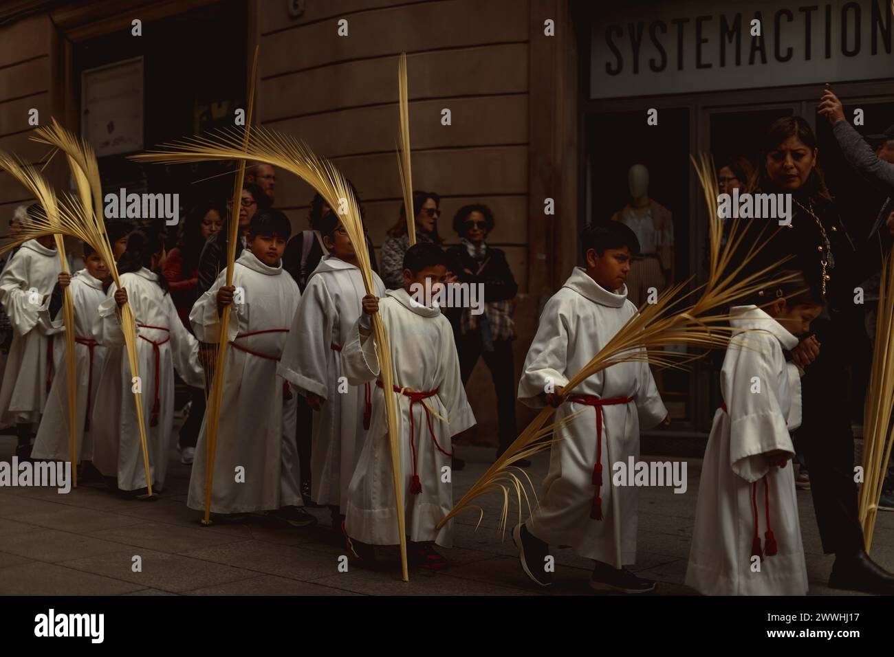Barcelona, Spanien. März 2024. Junge Pönitenten aus der 'Gran Poder und Macarena Esperanza'-Bruderschaft gehen während der Palmensonntagsprozession in Barcelona mit Palmenzweig durch die Straße. Credit: Matthias Oesterle/Alamy Live News Stockfoto
