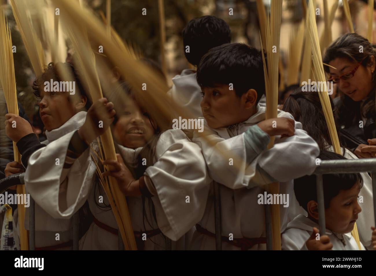 Barcelona, Spanien. März 2024. Junge Pönitenten der Bruderschaft Gran Poder und Macarena Esperanza winken Palmblätter, während der Priester sie am Ende der Palmensonntagsprozession in Barcelona segnet. Credit: Matthias Oesterle/Alamy Live News Stockfoto