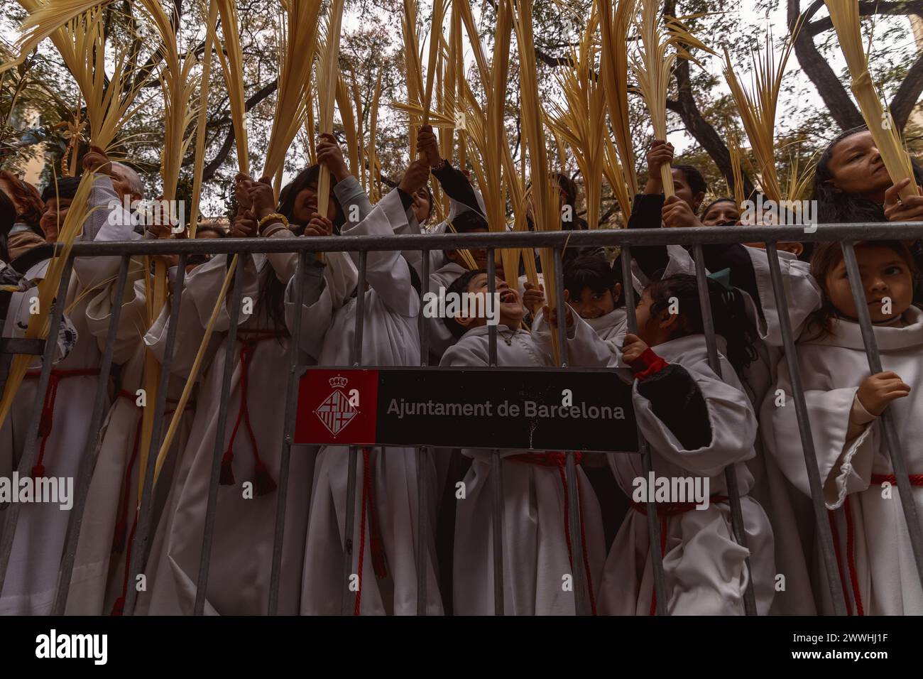 Barcelona, Spanien. März 2024. Junge Pönitenten der Bruderschaft Gran Poder und Macarena Esperanza winken Palmblätter, während der Priester sie am Ende der Palmensonntagsprozession in Barcelona segnet. Credit: Matthias Oesterle/Alamy Live News Stockfoto