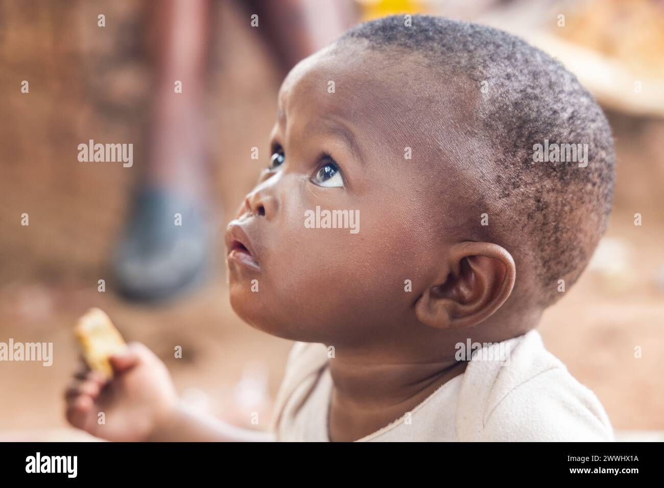 Der hungrige afrikanische Junge isst billige Kekse im Hof Stockfoto