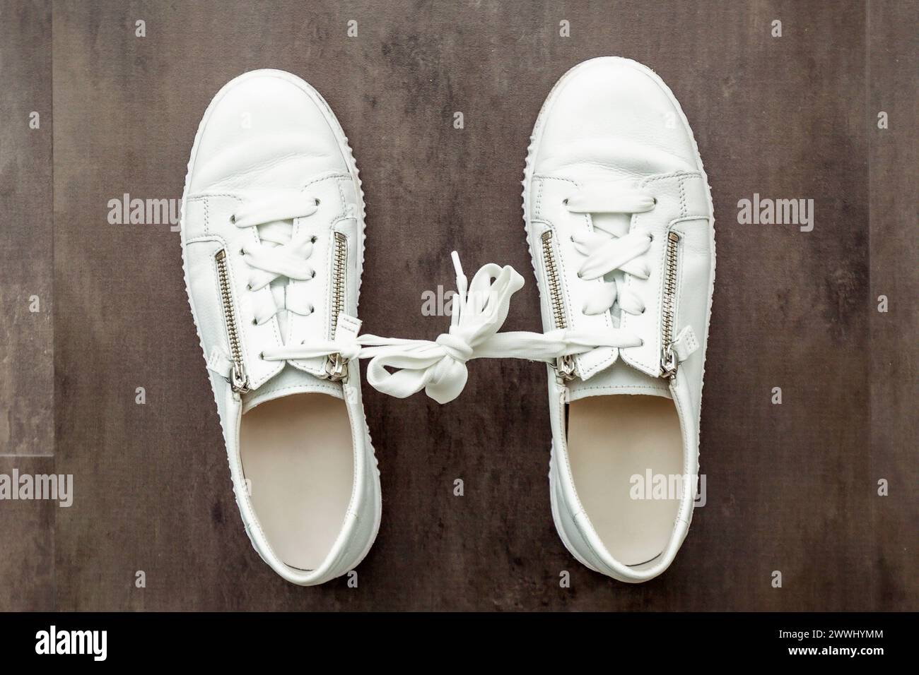 Gamophobie. Angst vor dem Engagement. Ein Paar weiße Schuhe, Sneaker auf hölzernem Hintergrund. Gamophobie. Angst vor Co-Gamophobie. Furcht vor engagierten Menschen Stockfoto