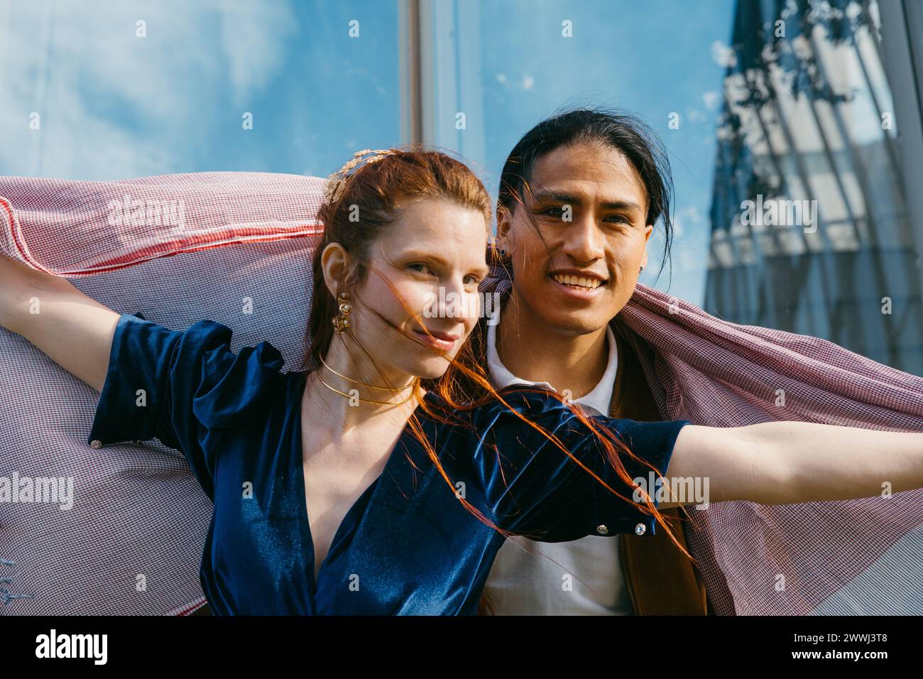 Lächelnde Gesichter und ein gemeinsamer Schal verkörpern die Wärme und den Genuss zweier Freunde auf einer Stadtbesichtigung. Stockfoto