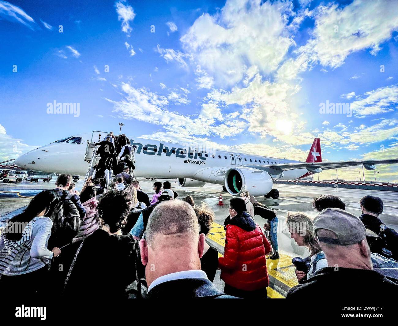 Boarding mit Passagieren auf dem Rollfeld des Flughafens der Schweizer Fluggesellschaft Helvetic Airways, die im Auftrag der Swiss operiert. Embraer 195 Schweiz *** Einsteigen mit Fluggästen auf dem Rollfeld am Flughafen der Schweizer Fluggesellschaft Helvetic Airways, die im Auftrag der Swiss Embraer 195 Schweiz tätig ist Copyright: XJoeranxSteinsiekx Stockfoto