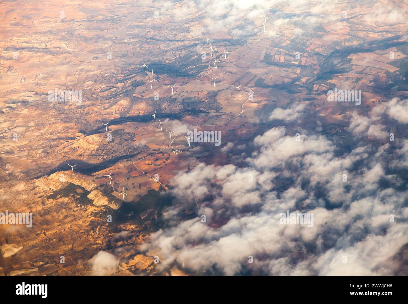 Berge der südlichen Alpen mit Windgeneratoren während des Sonnenuntergangs, Blick aus dem Flugzeug Stockfoto
