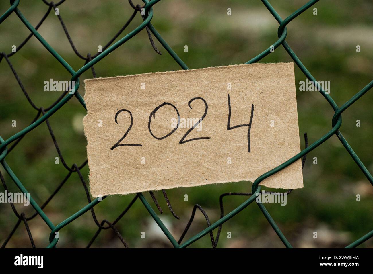 Ein braunes Stück Papier mit dem Text 2024 hängt als Hintergrund auf dem Zaun, das Jahr 2024 Stockfoto