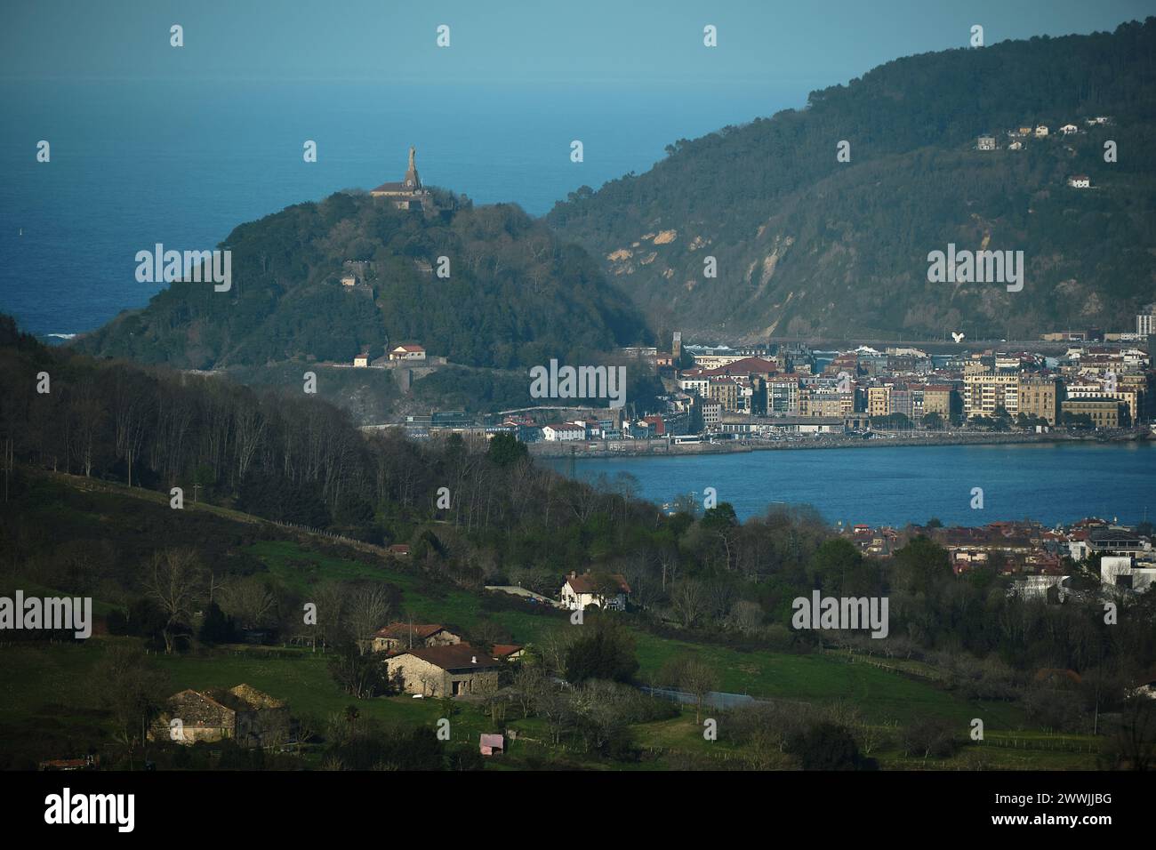 Landschaftsfotografie mit einem antiken Aussehen, es ist eine Bucht umgeben von Bergen mit modernen Gebäuden und alten Hirtenhäusern, alle in Grün und Stockfoto