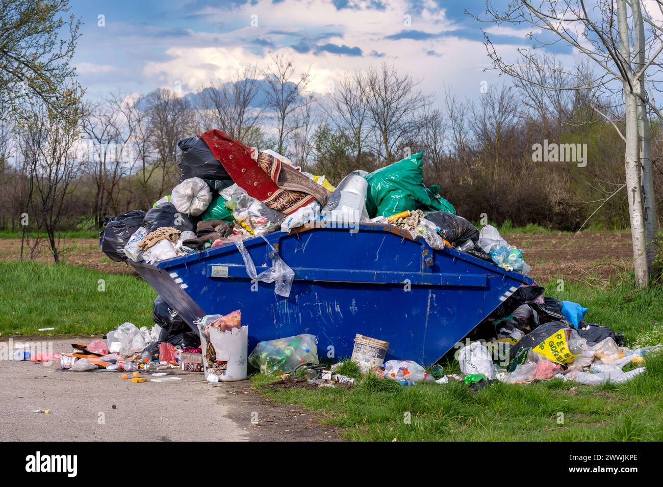 VUKICEVICA, SERBIEN - 02. APRIL. 2023: Ein Haufen Müll aus Lebensmittelabfällen, Dosen, Plastikflaschen und Plastiktüten wird aus einem überfüllten Behälter verstreut. Stockfoto