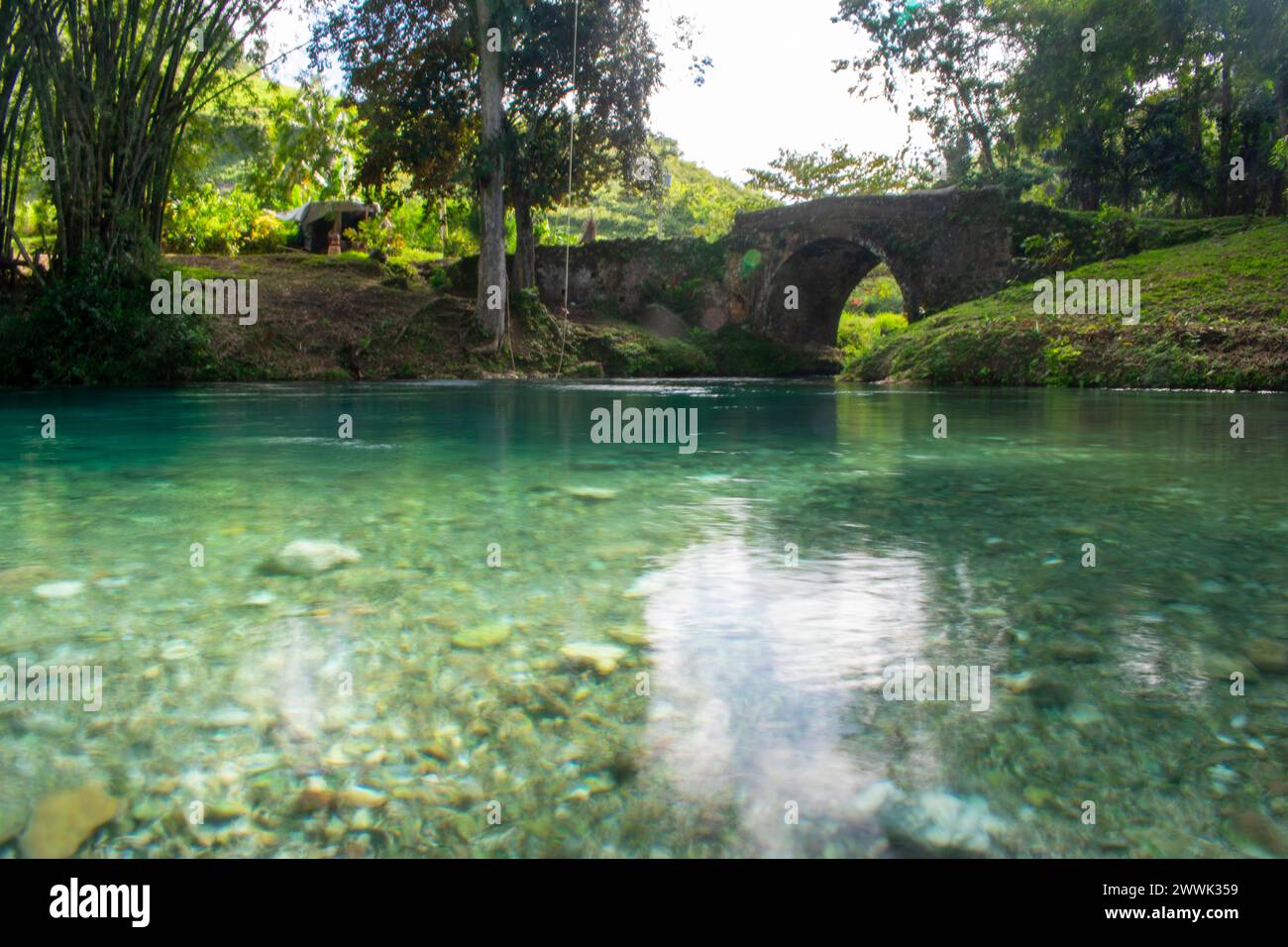 Alte spanische Brücke im White River, Saint Mary, Jamaika klares grünes Wasser reflektiert den Himmel Stockfoto