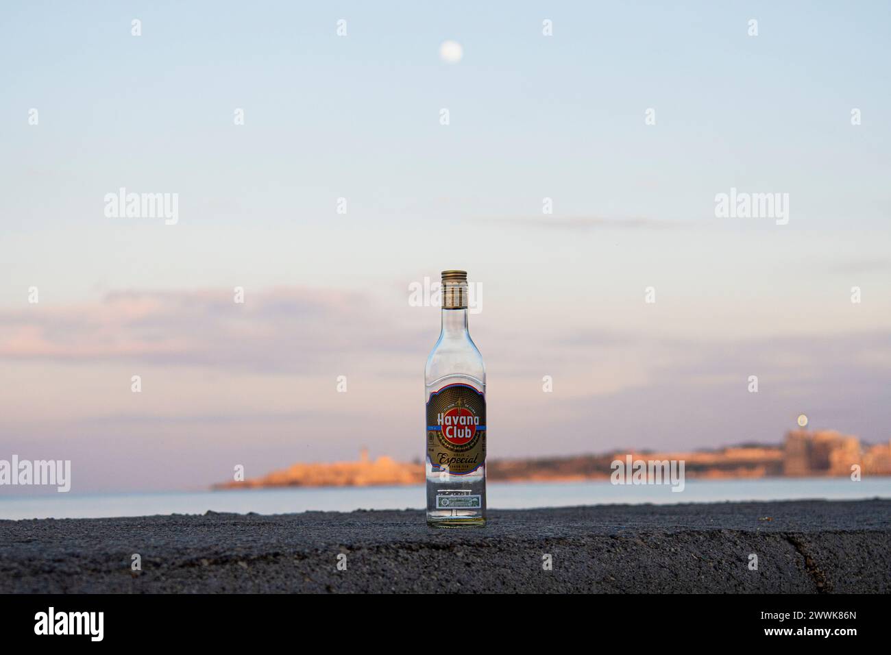Die Sonne untergeht über dem Malecon in Havanna, Kuba, über einer leeren Flasche Havana Club Cuban Rum. Stockfoto