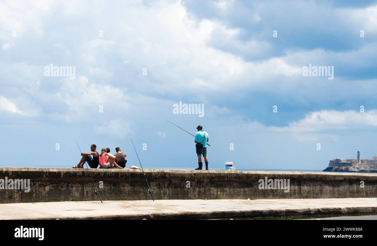 Die Menschen entspannen und fischen an der Meeresmauer vor dem Fort El Malecon in Havanna, Kuba. Stockfoto