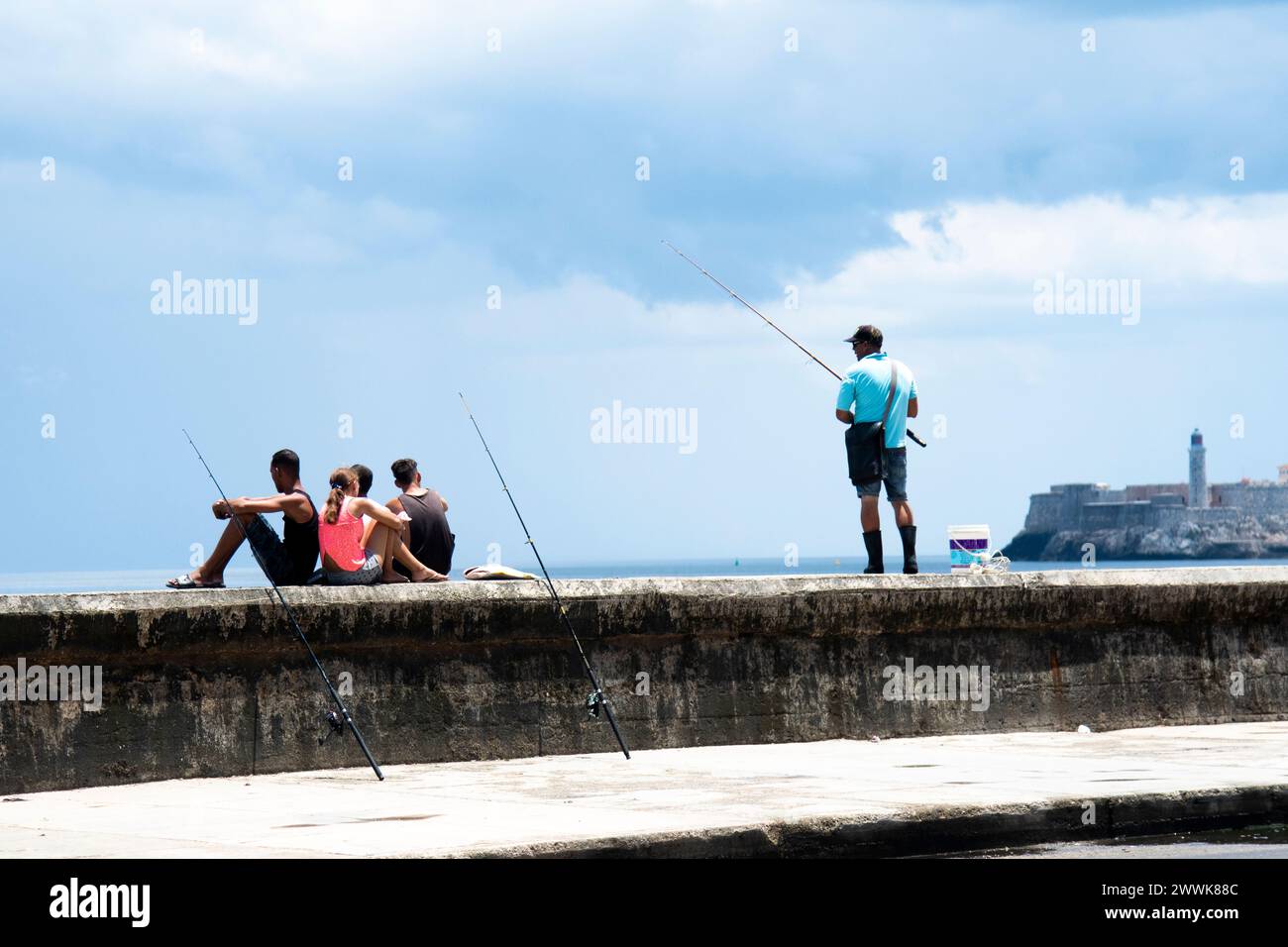 Die Menschen entspannen und fischen an der Meeresmauer vor dem Fort El Malecon in Havanna, Kuba. Stockfoto