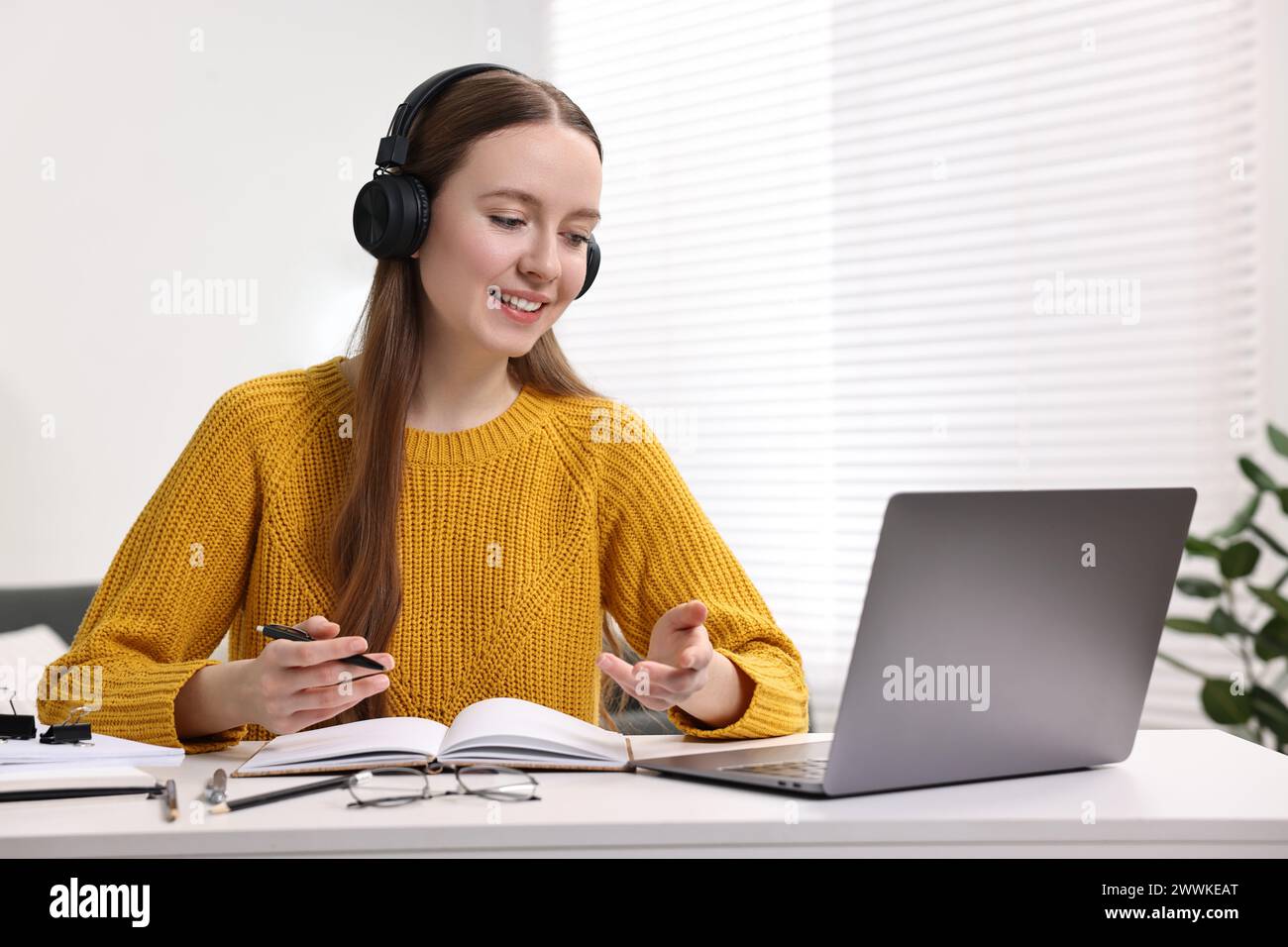 E-Learning. Junge Frau, die beim Online-Unterricht an einem weißen Tisch drinnen einen Laptop benutzt Stockfoto