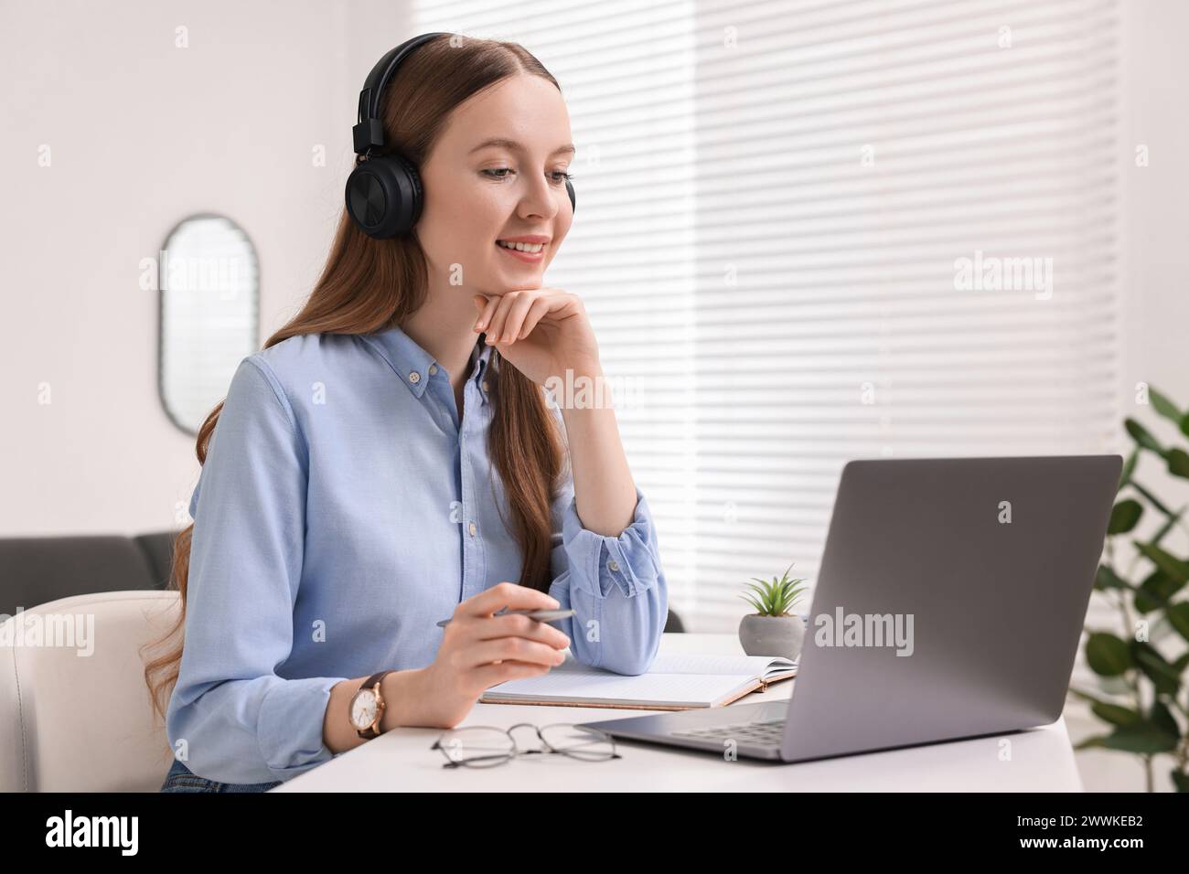E-Learning. Junge Frau, die beim Online-Unterricht an einem weißen Tisch drinnen einen Laptop benutzt Stockfoto